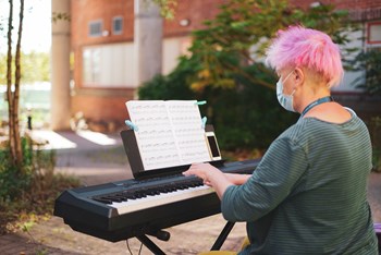 Woman in mask playing keyboard outside